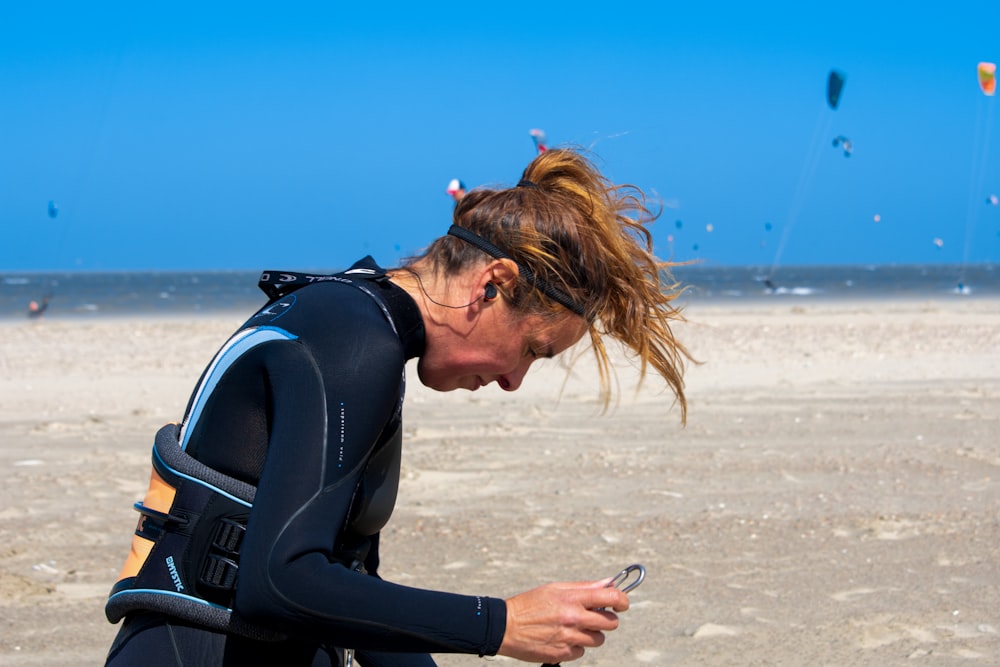 a woman sitting on the beach looking at her cell phone