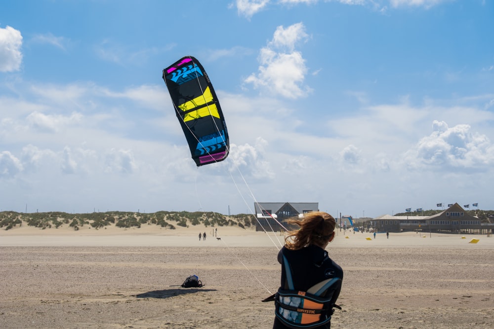 a person standing on a beach flying a kite