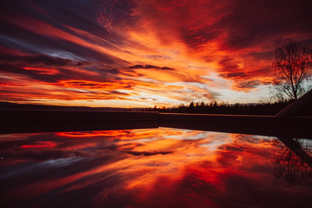a red and orange sky reflecting in a body of water