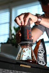 An Aeropress coffee maker with freshly brewed coffee in a clear glass.