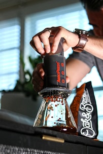 An Aeropress coffee maker with freshly brewed coffee in a clear glass.