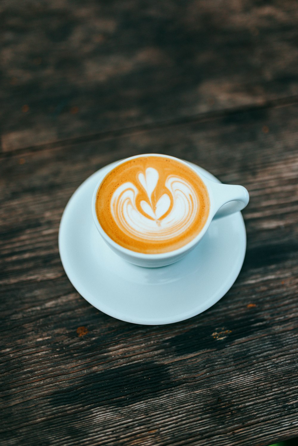 a cappuccino on a saucer on a wooden table