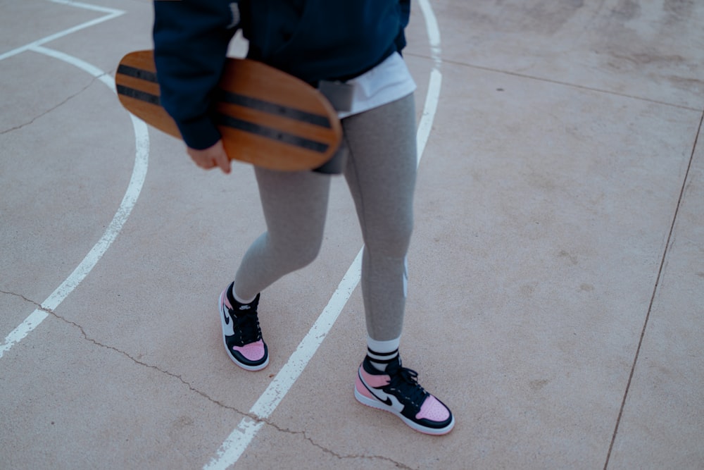 une personne debout sur un terrain de basketball tenant une planche à roulettes