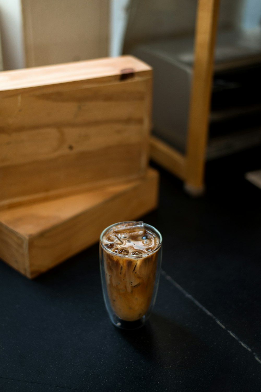 a glass of iced coffee next to a wooden box