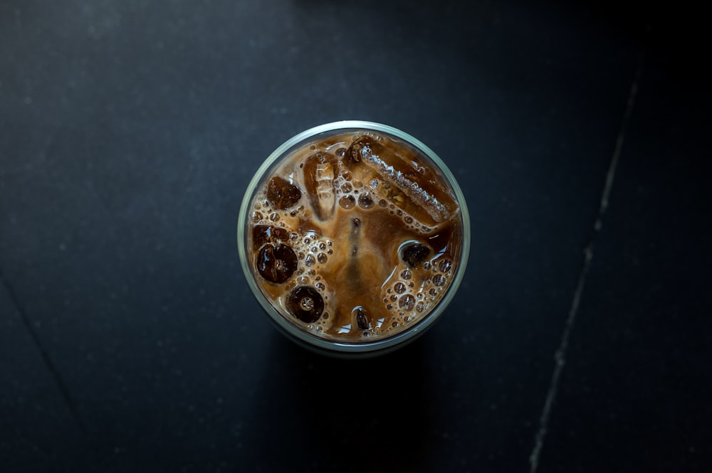 a glass of iced coffee on a black table