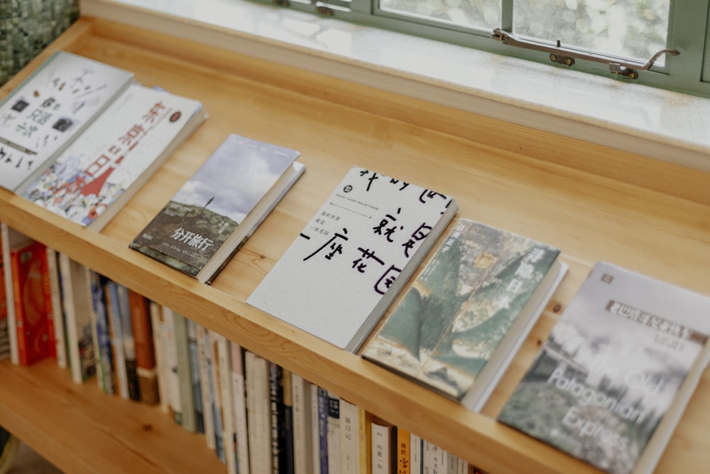 a bookshelf filled with lots of books next to a window