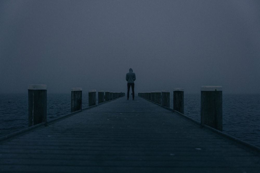 a person standing on a pier in the dark