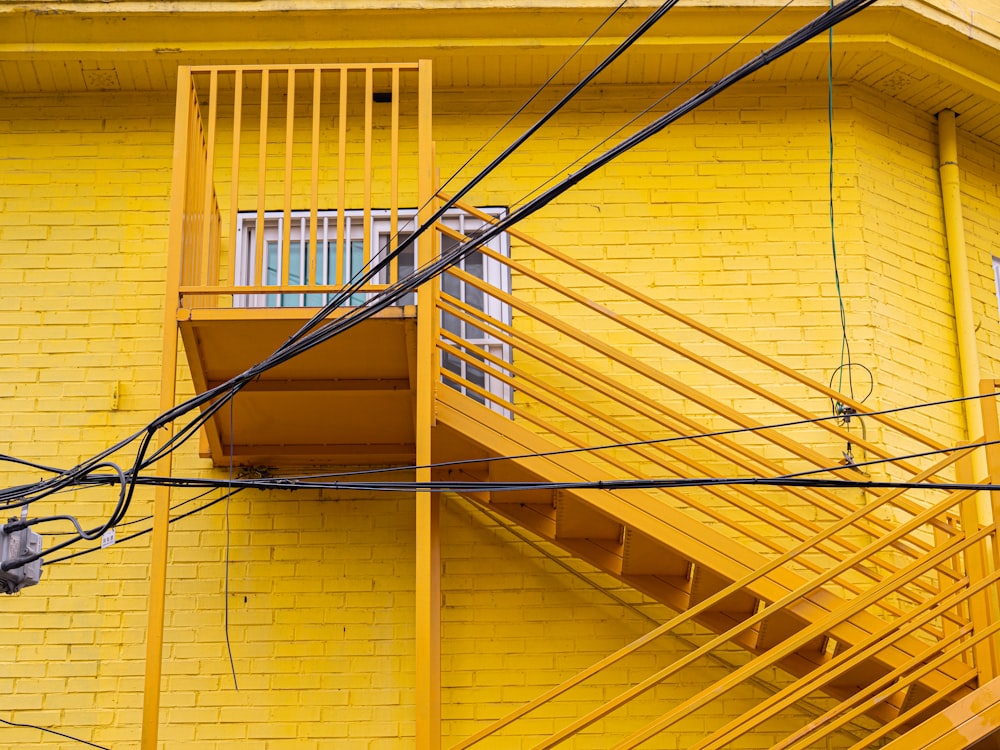 a yellow building with a staircase and a balcony