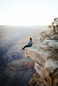 a person sitting on top of a cliff