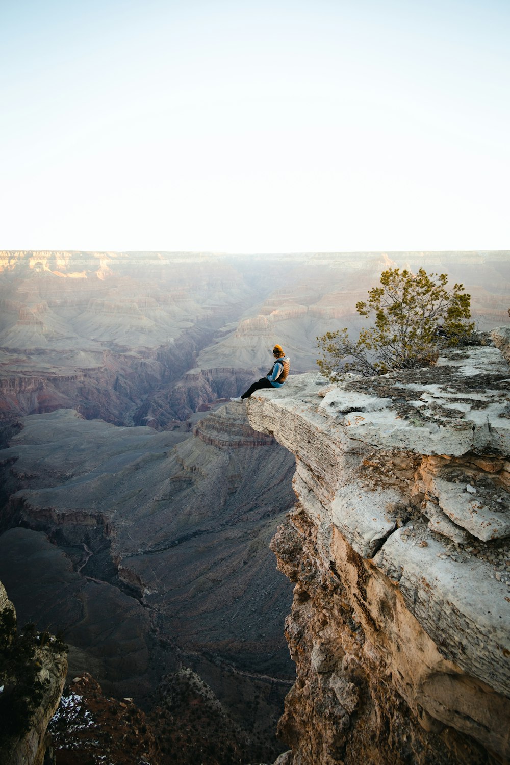 Un homme assis au sommet d’une falaise surplombant un canyon