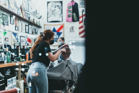 a woman cutting a mans hair in a barber shop