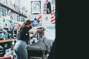 a woman cutting a man's hair in a barber shop