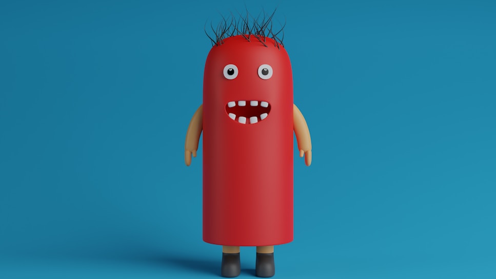 A whimsical, cartoonish character with a cylindrical, red body resembling a hot dog stands against a blue background. It has googly eyes, a wide open mouth with a few white teeth, spiky black hair, and tan-colored arms and brown shoes.