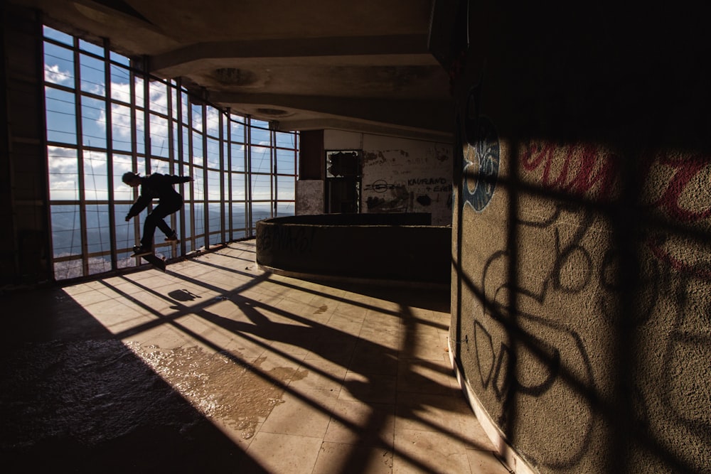 a man riding a skateboard down a hallway next to a window