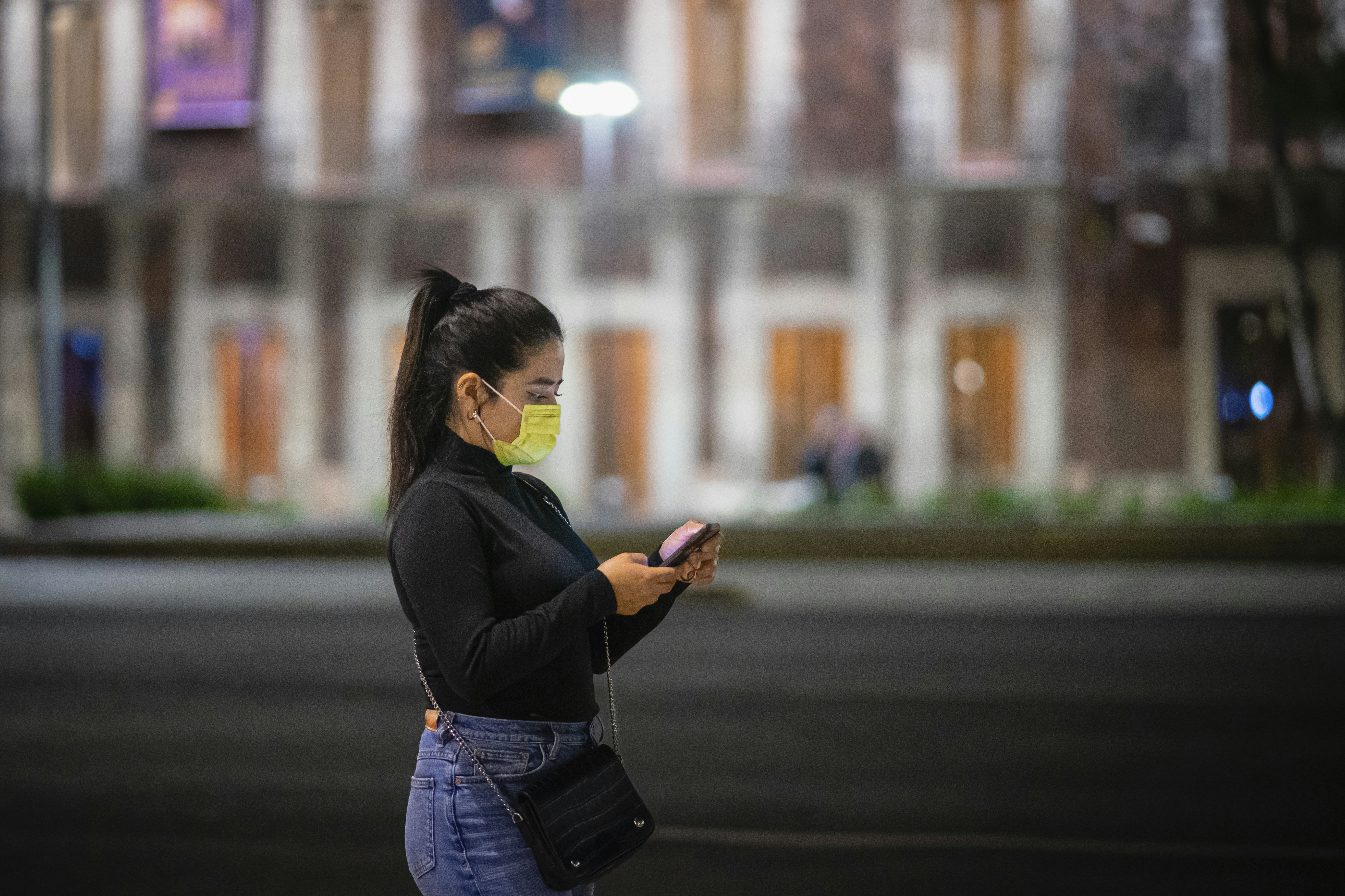 a woman wearing a face mask while looking at her cell phone