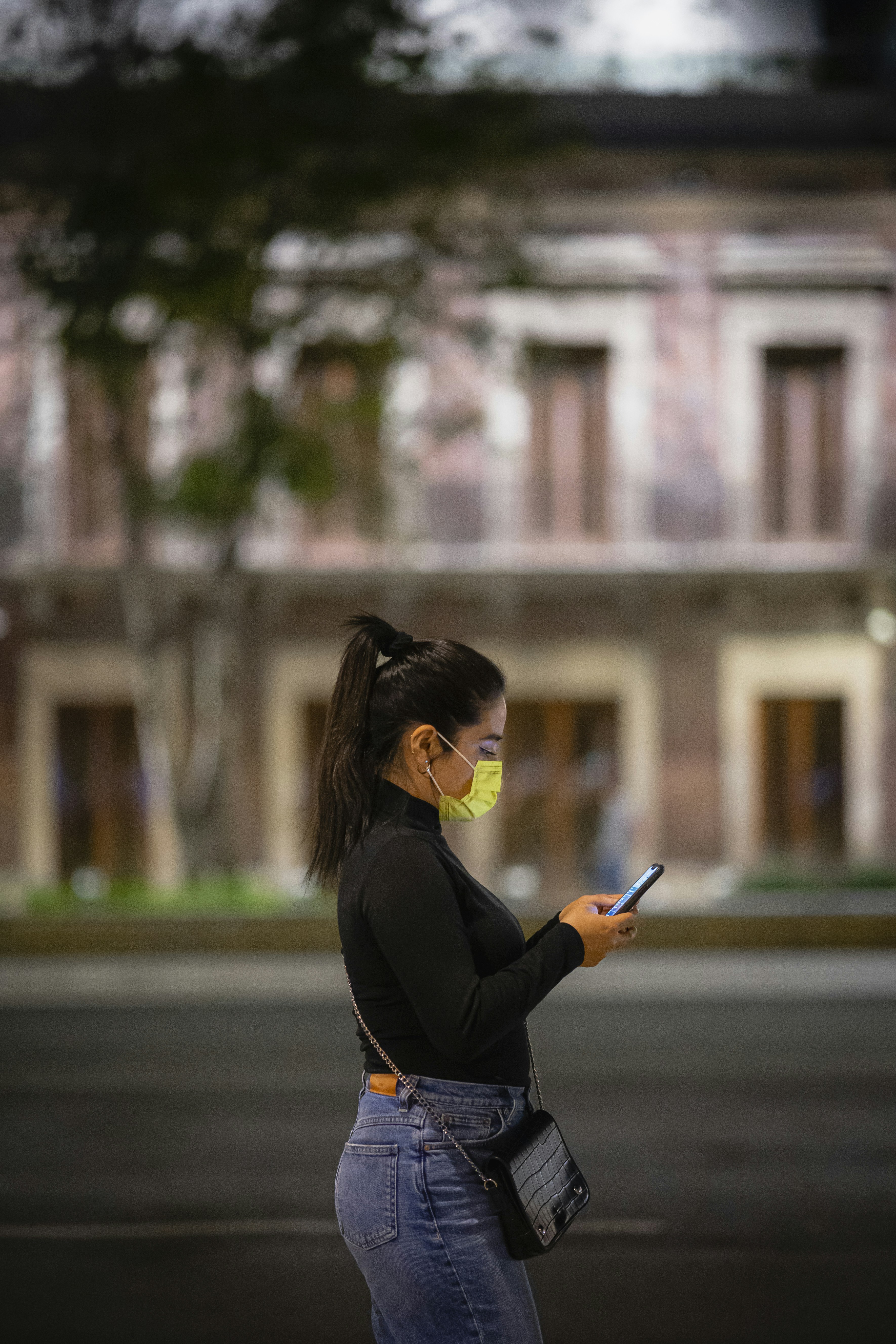 a woman wearing a face mask while looking at her cell phone