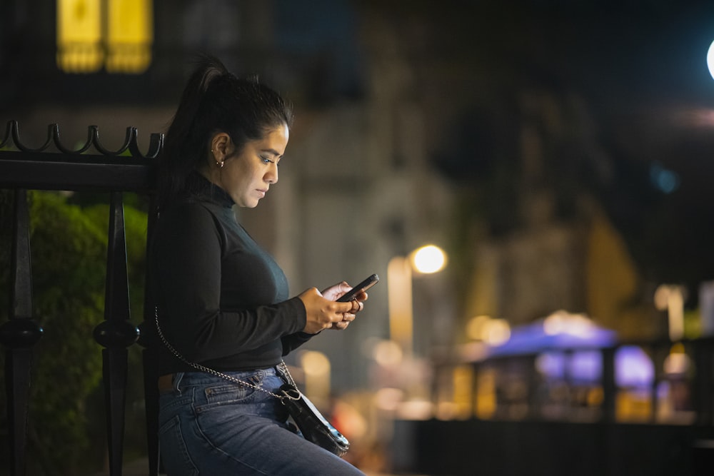 a woman sitting on a bench looking at her cell phone