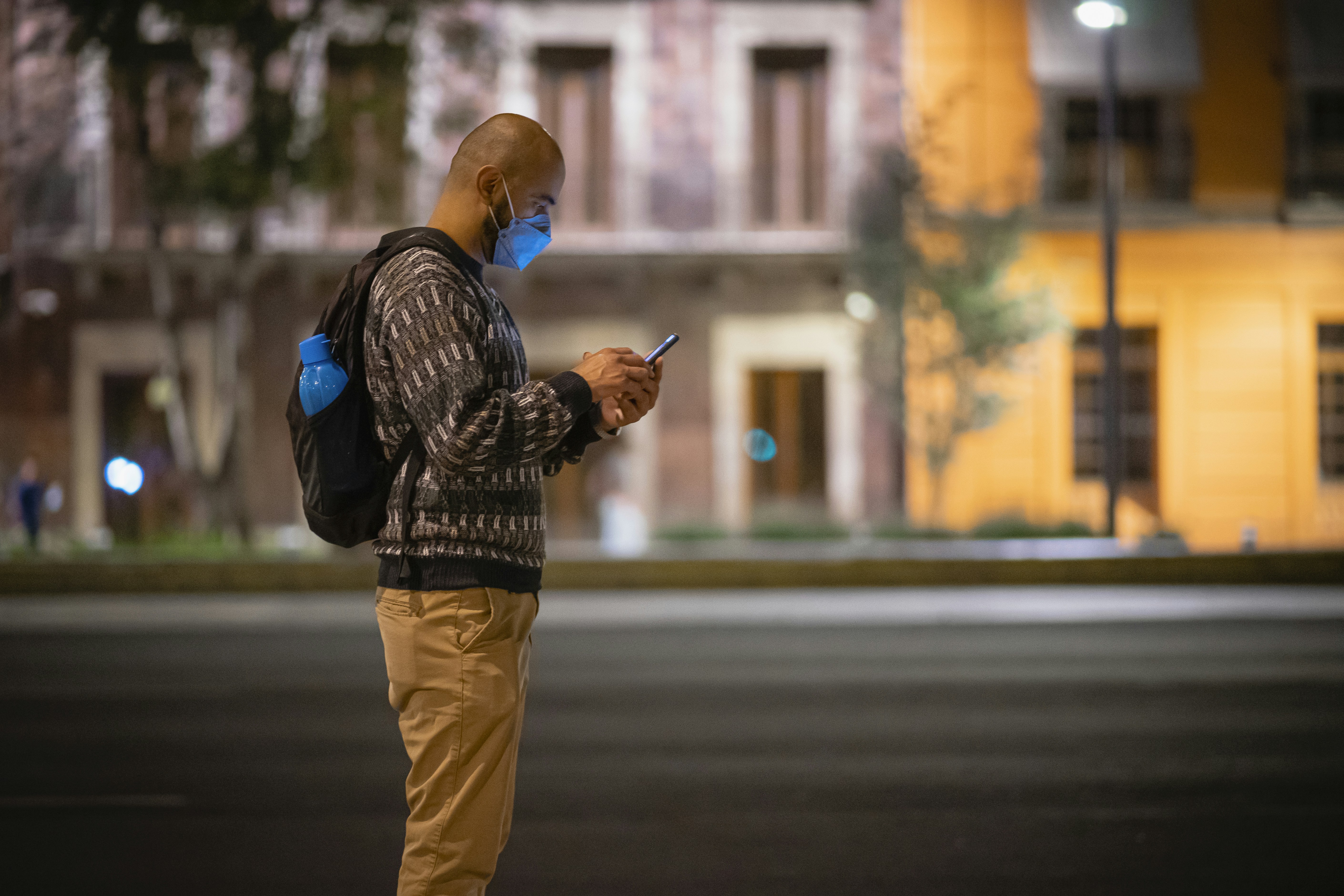 a man wearing a face mask while looking at his cell phone