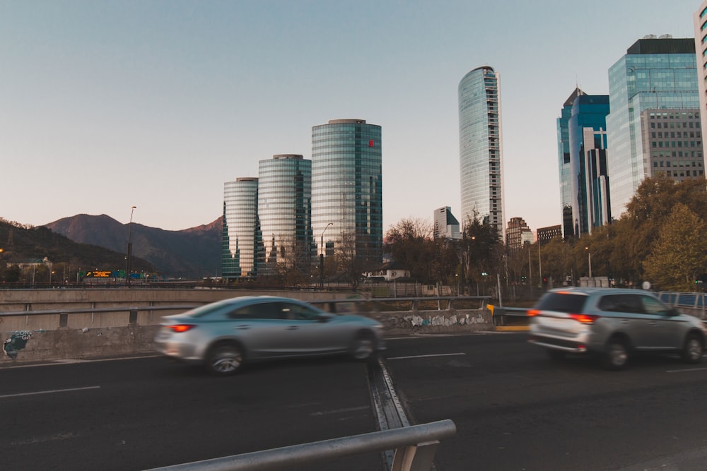 a couple of cars driving down a street next to tall buildings