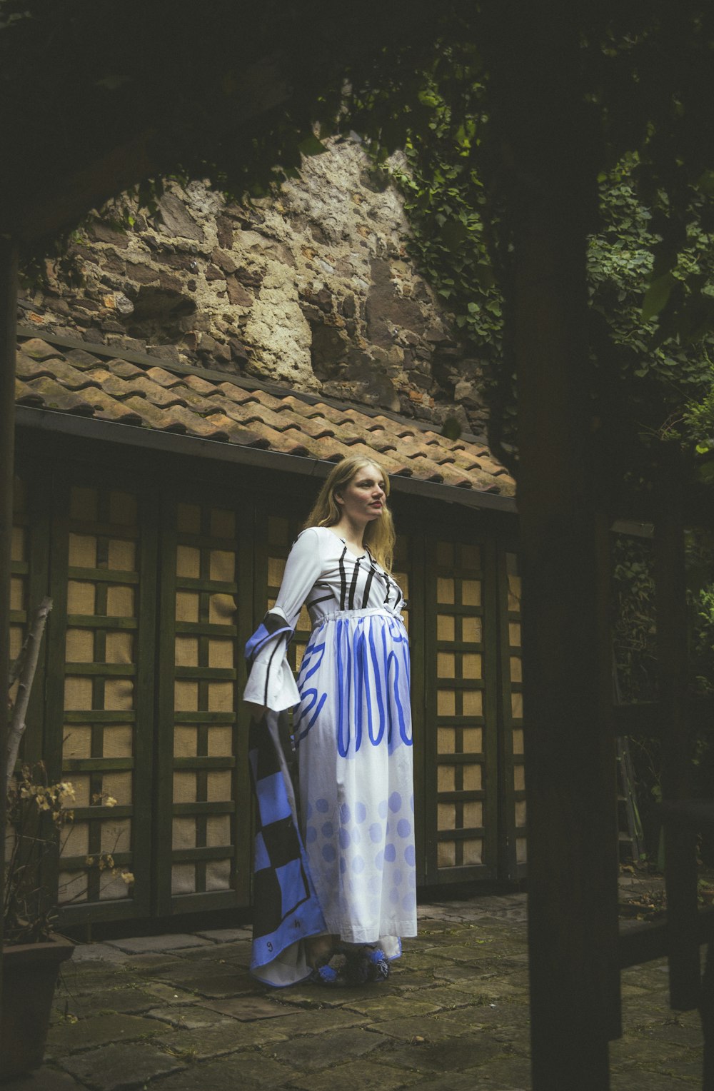 a woman in a blue and white dress standing in front of a building