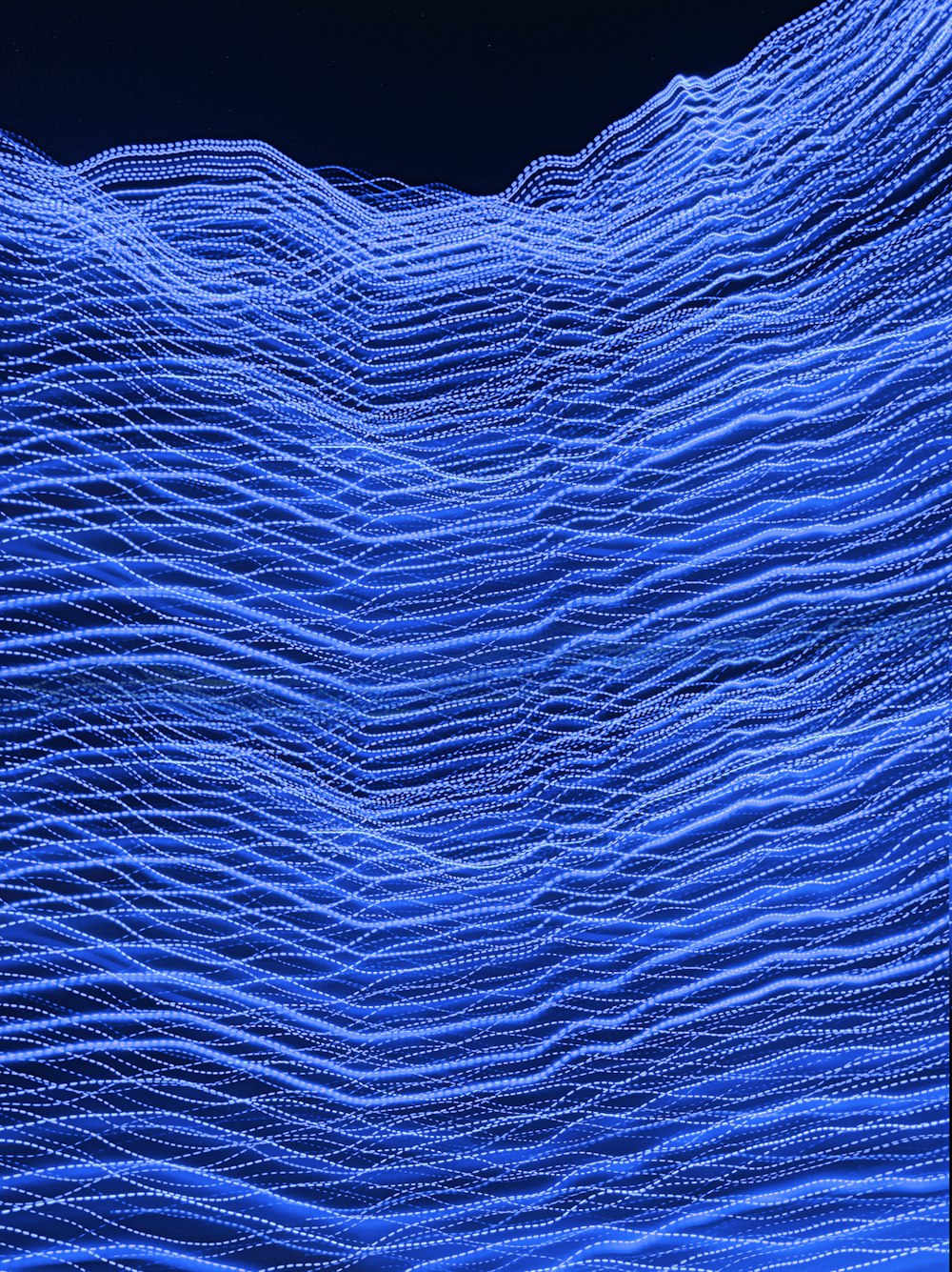 a large blue wave is shown in the night sky