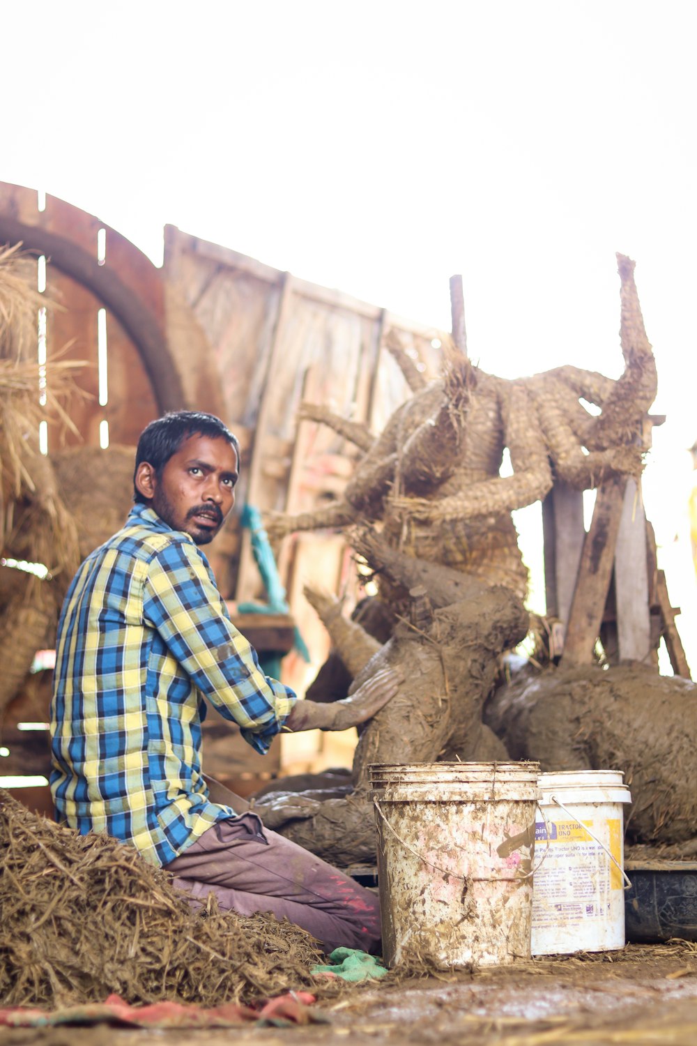 a man sitting on a pile of hay next to a bucket