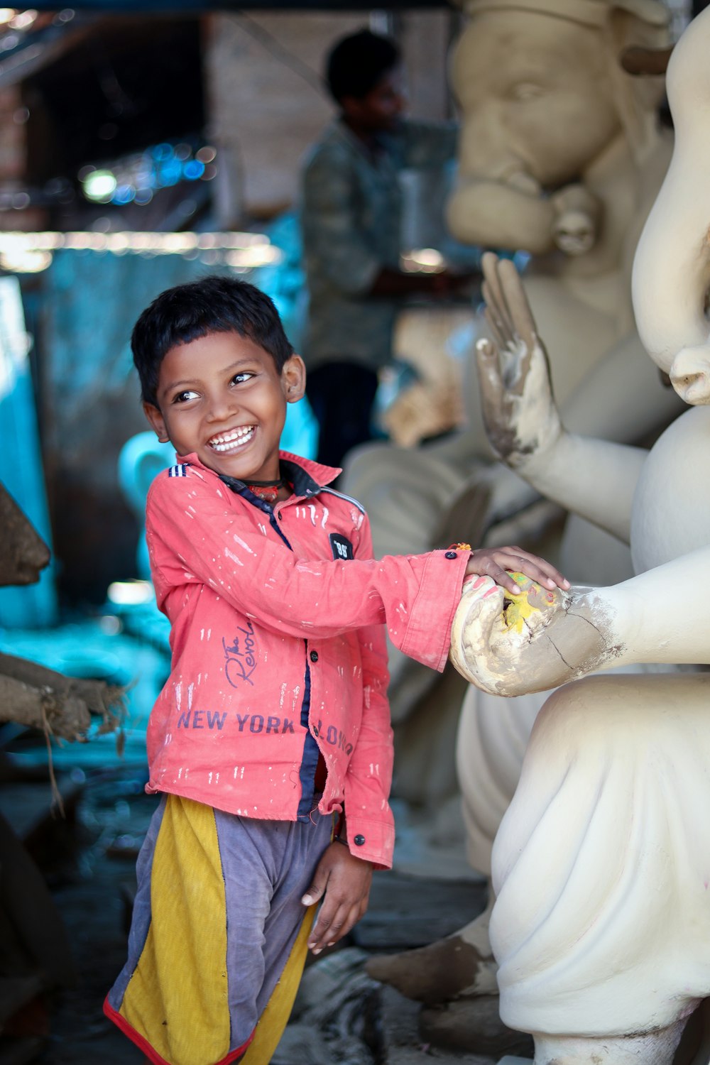 a young boy standing next to a white statue