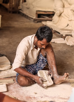 a man sitting on the ground working on a piece of pottery