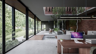 A modern office space with large glass windows providing a view of lush greenery outside. The interior features a mix of contemporary and natural elements, including brick walls and indoor plants. Desks are equipped with computer monitors and stationery. A wooden floor section adds warmth to the sleek, minimalistic design. Abundant natural light enhances the open and airy atmosphere.