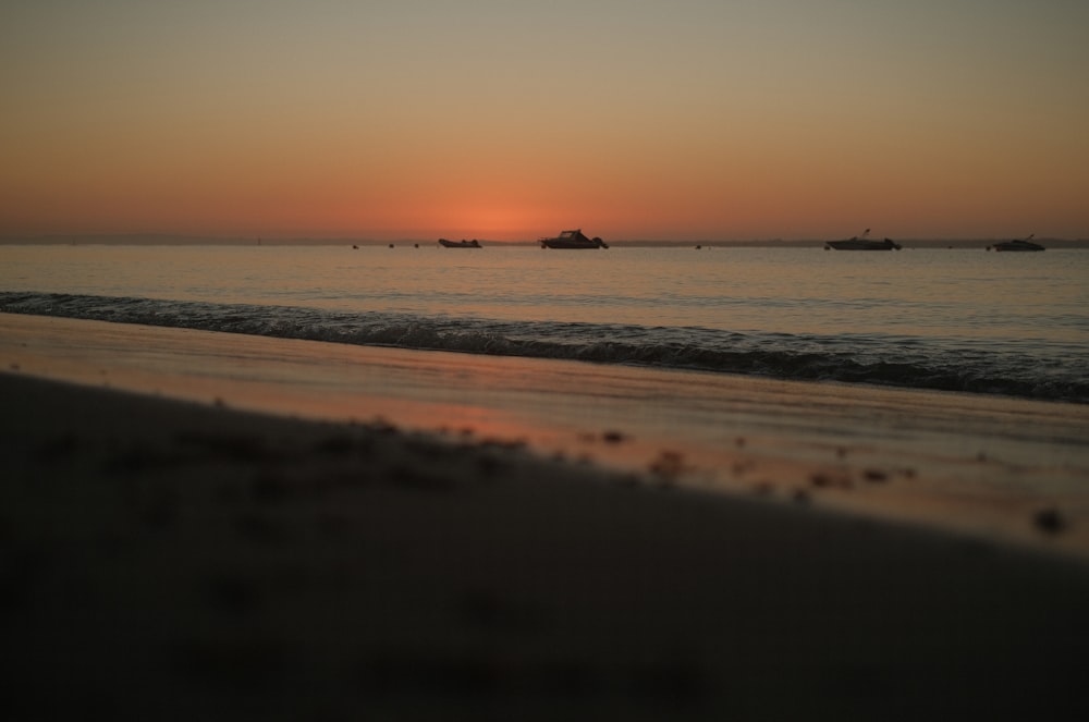 a sunset over the ocean with boats in the distance