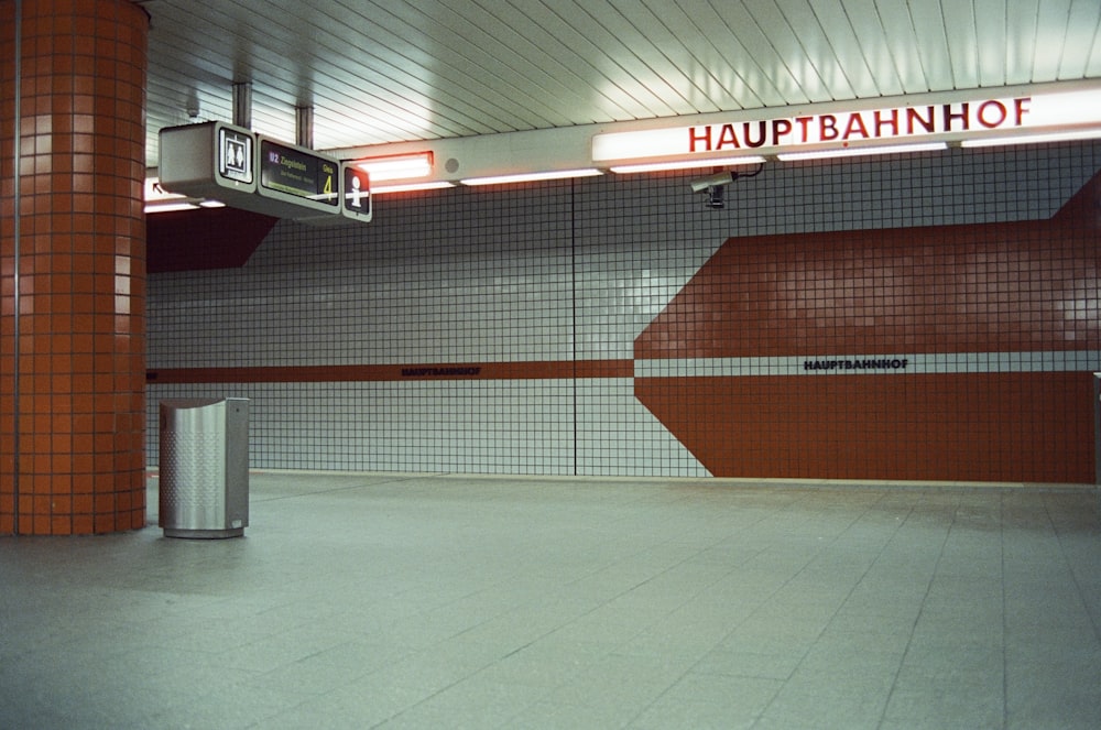 an empty subway station with a red and white sign