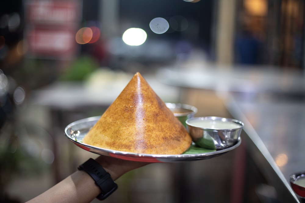 a person holding a plate with a cone on it