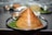 A crispy, cone-shaped dosa is placed on a stainless steel plate lined with a banana leaf. Accompanying the dosa are small bowls containing different chutneys.