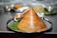 A close-up of a golden crispy masala dosa with spiced potato filling steaming on a banana leaf.