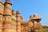 Historic Omani fort with intricate stonework and visitors admiring the architecture on a clear day.