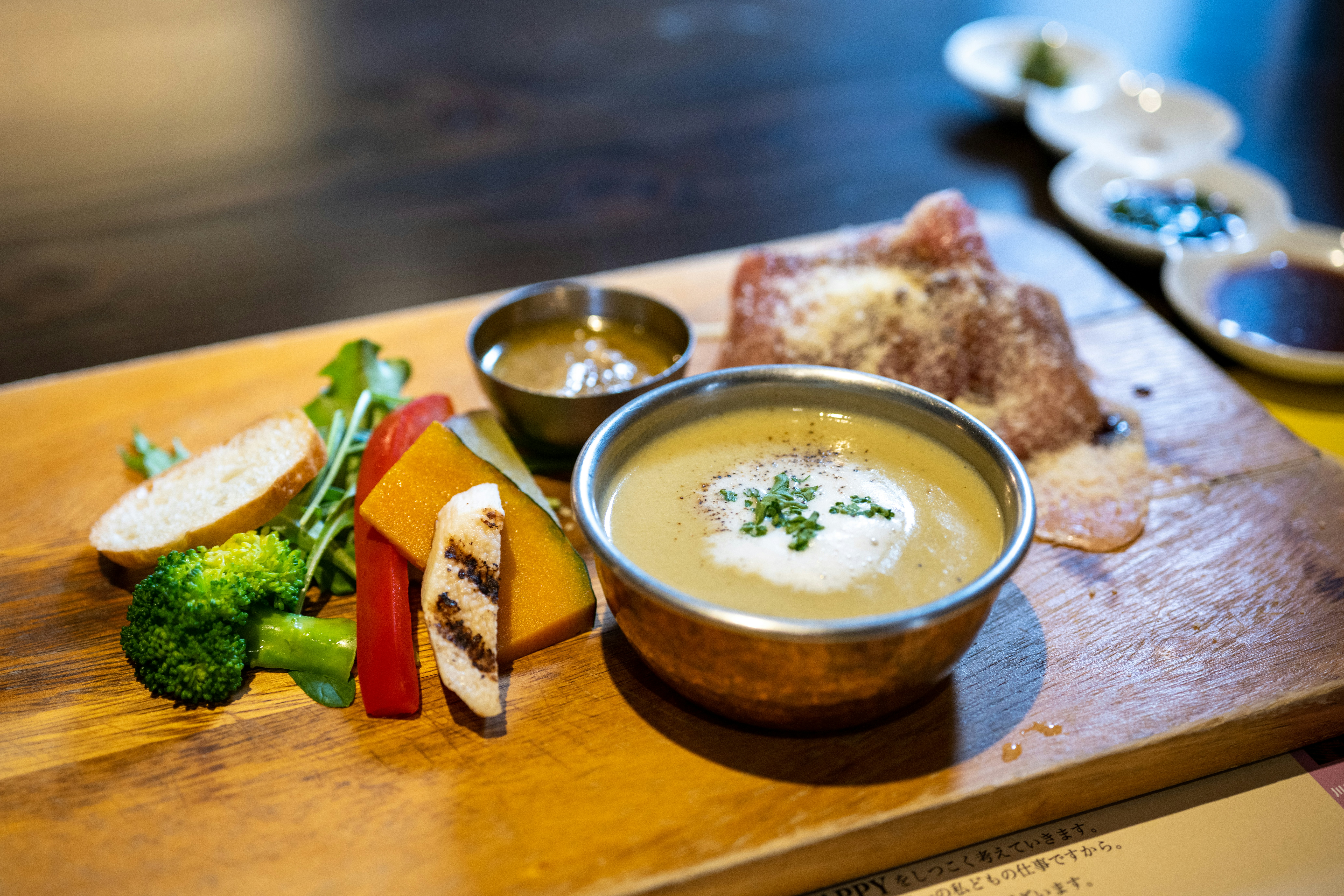 a wooden cutting board topped with a bowl of soup