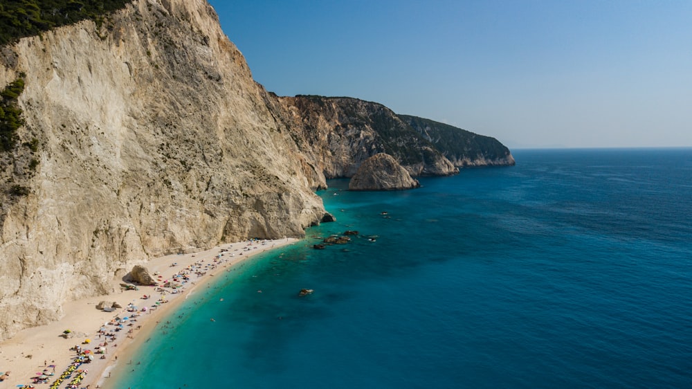 a group of people on a beach next to a cliff