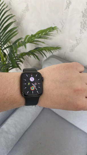 A cozy living room with a senior using a smartwatch and a medical alert device on the table.