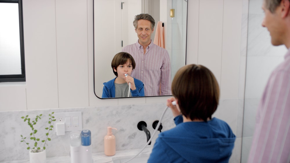 a man standing in front of a bathroom mirror brushing his teeth