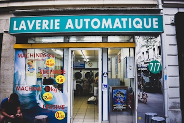 Modern laundry kiosk with customers using machines in a busy Kinshasa gas station.