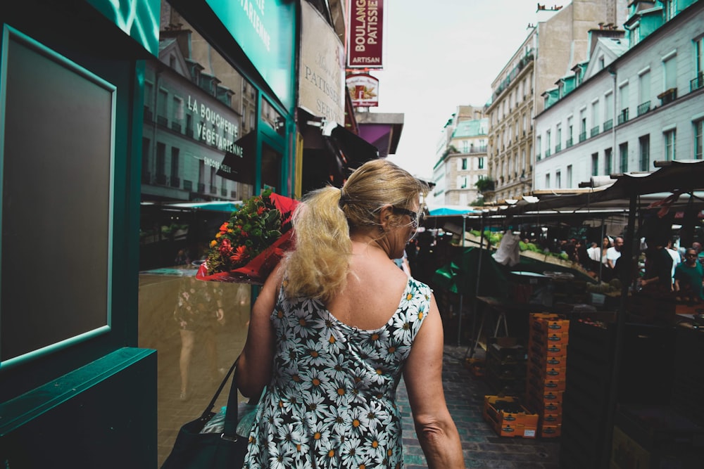 a woman walking down a street next to tall buildings