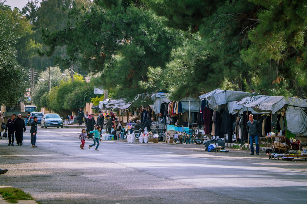 Eine Gruppe von Menschen geht eine Straße neben Zelten entlang