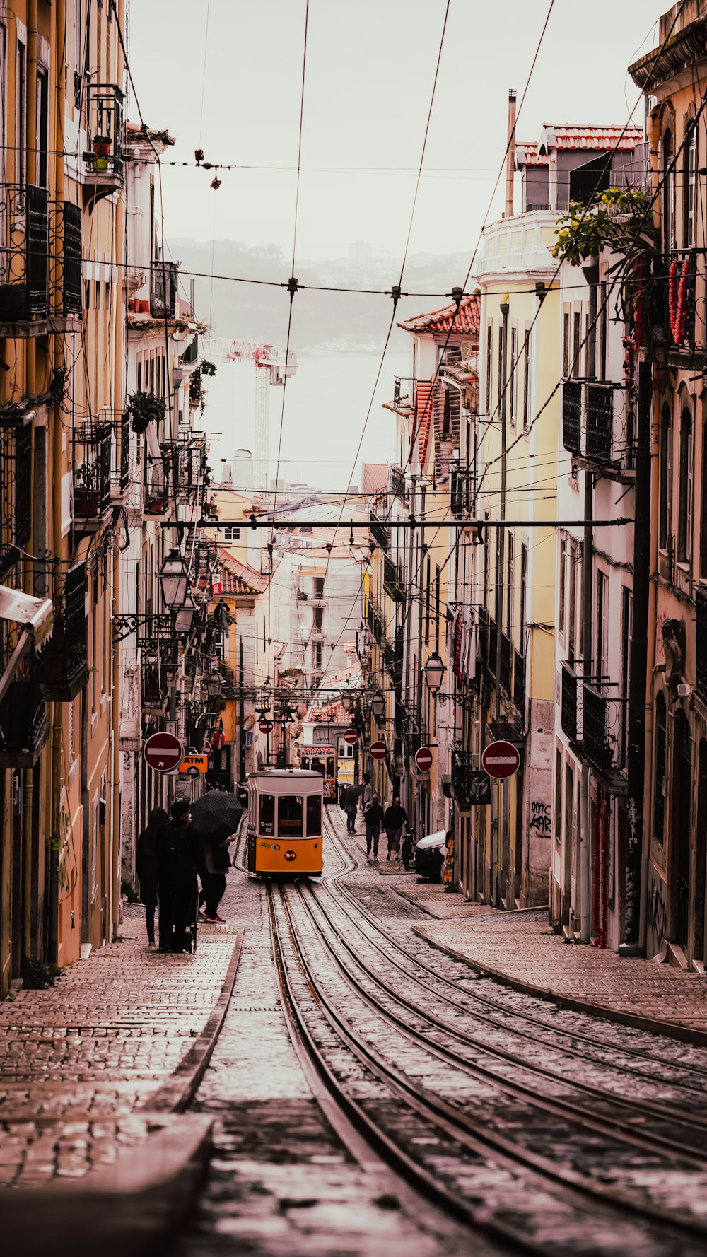 a yellow trolley car traveling down a street next to tall buildings