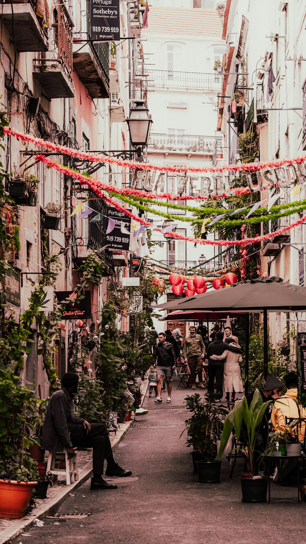 a narrow city street with people sitting and walking