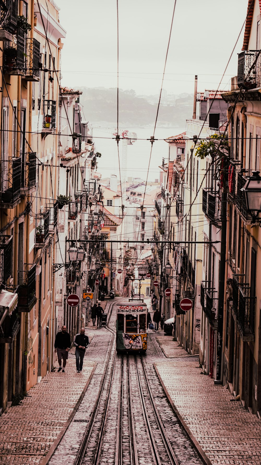 a couple of people walking down a street next to a train