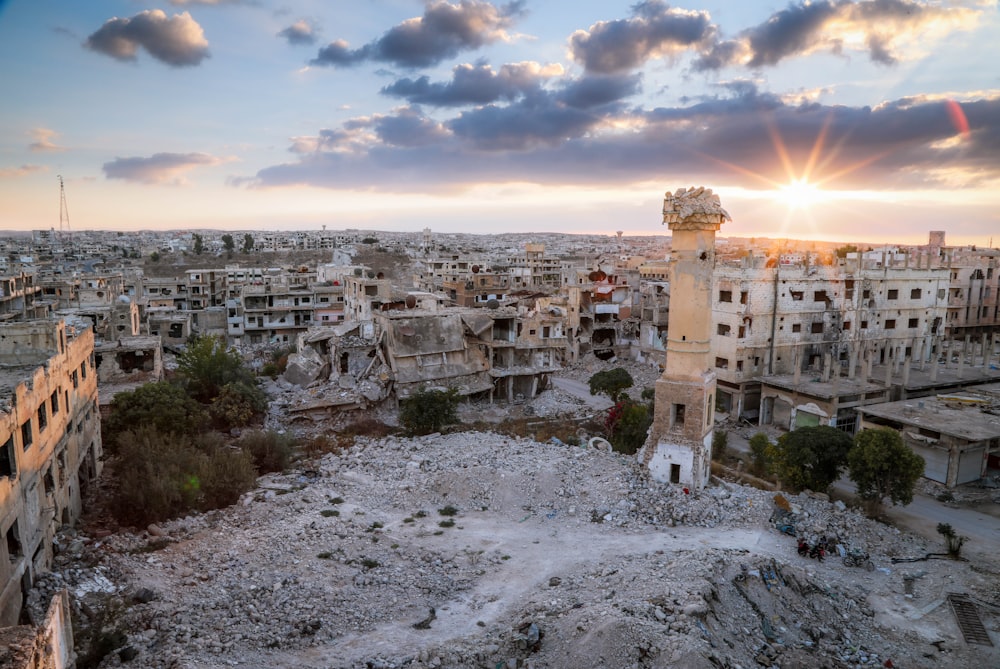 the sun is setting over the ruins of a city