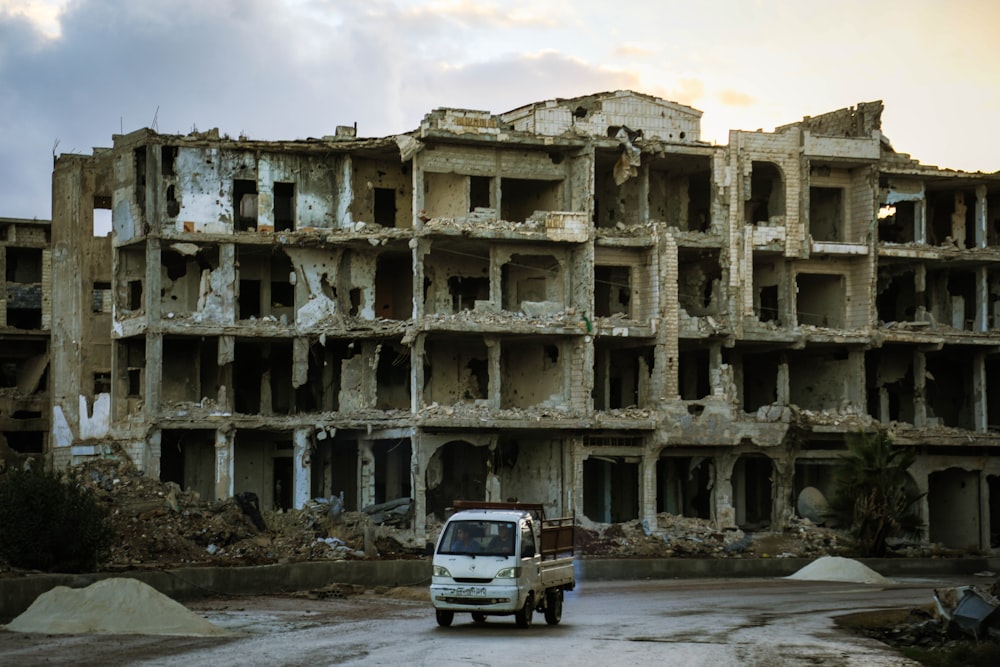 a white truck driving past a very large building