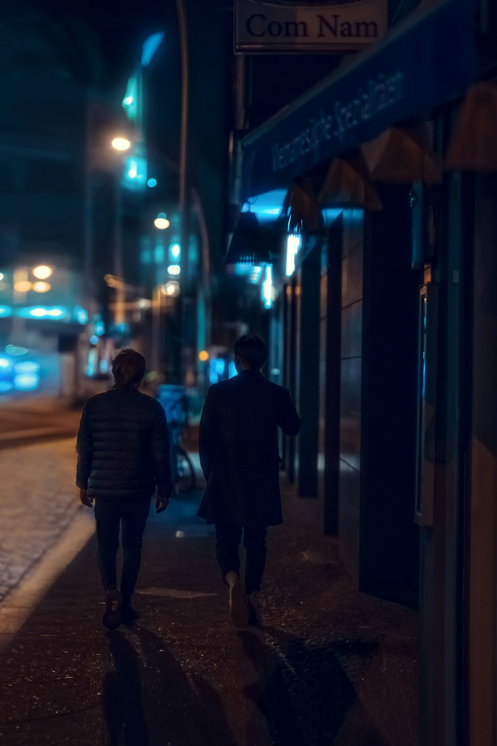 two people walking down a sidewalk at night