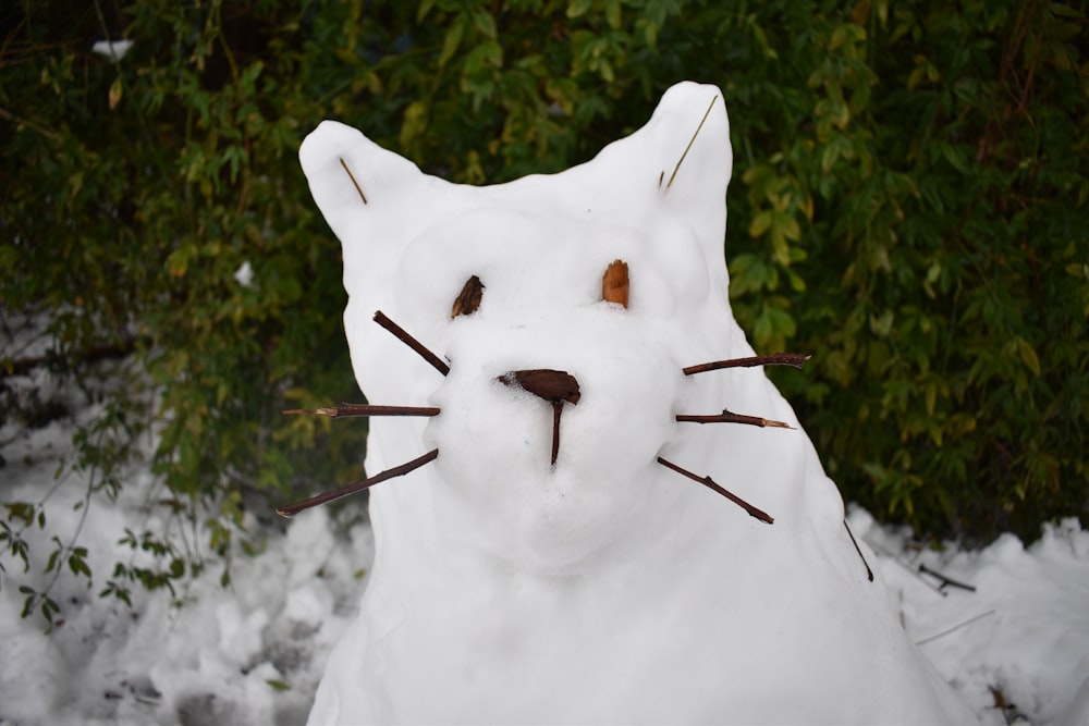 Eine weiße Katzenstatue ist mit Schnee bedeckt