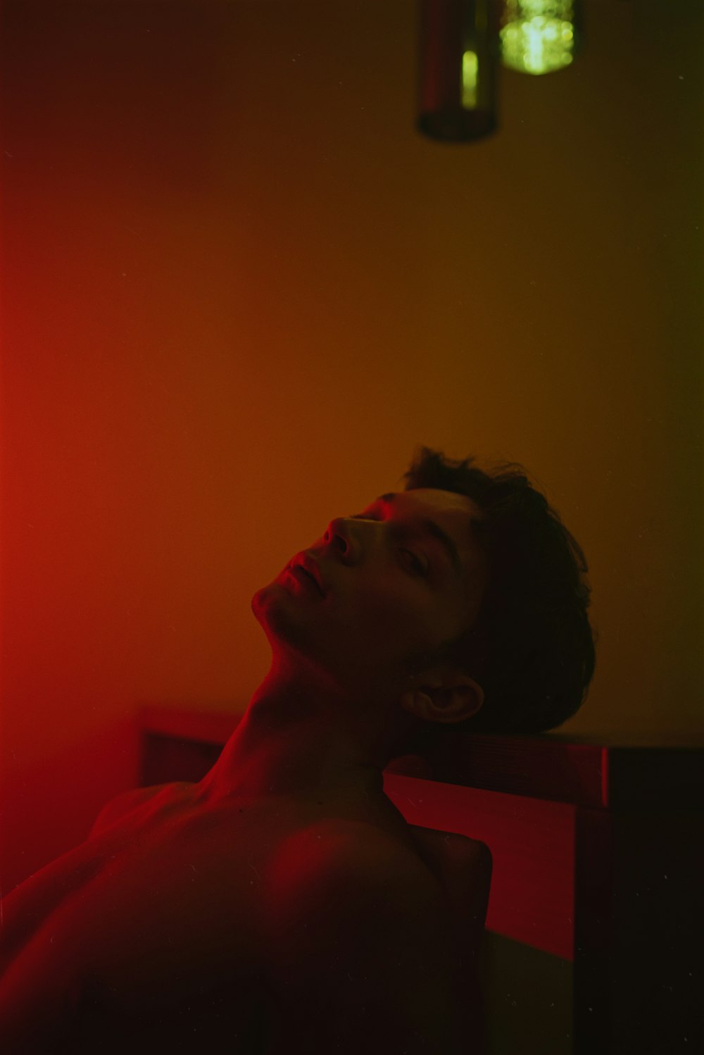a shirtless man sitting in a room with a red light